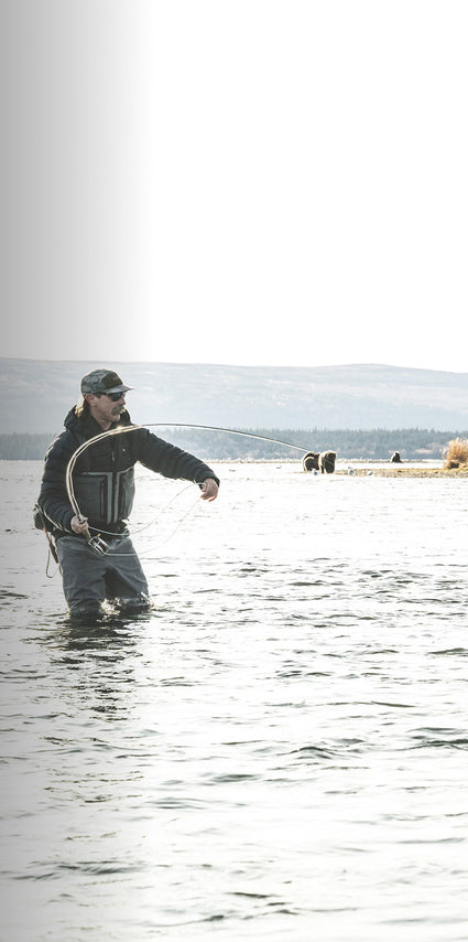 Man fly fishing in a body of water with a scenic background