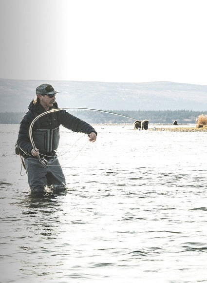 Man fly fishing in a body of water with a scenic background