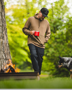 Man walking with a dog near a campfire in a forest