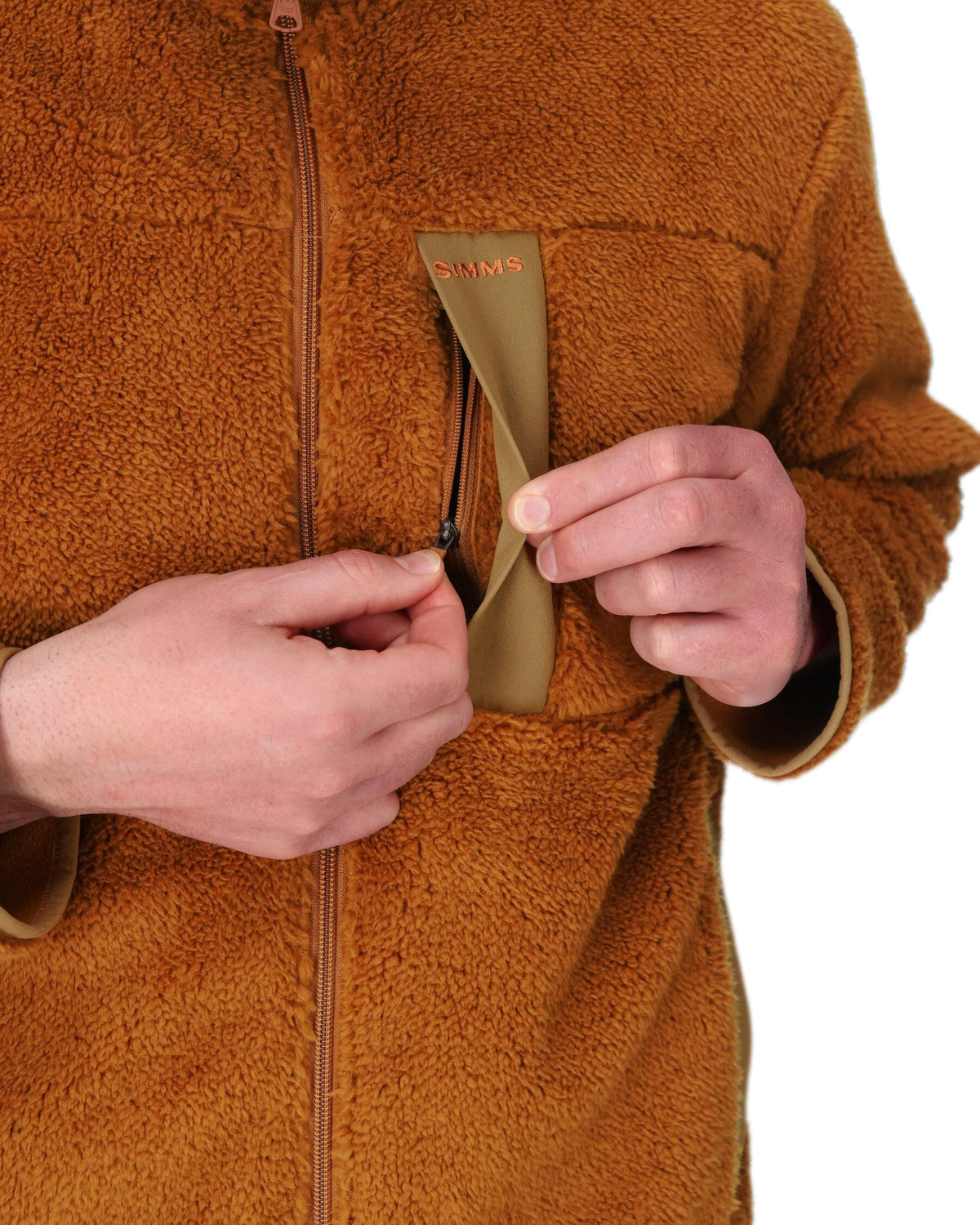 Person wearing a brown fleece jacket with a patch on a white background. 