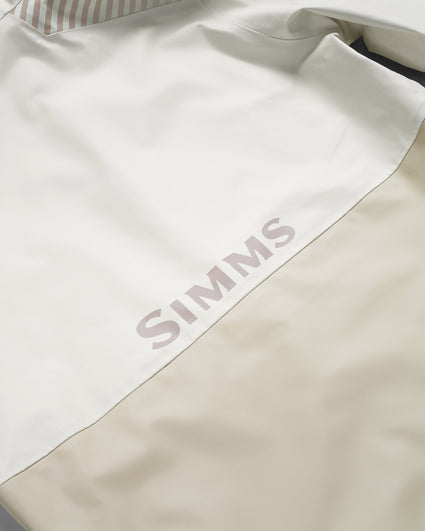 Close-up of a white and beige color-blocked garment with the brand name 'SIMMS' printed in a muted pinkish-beige font across the color-block seam. Alabaster