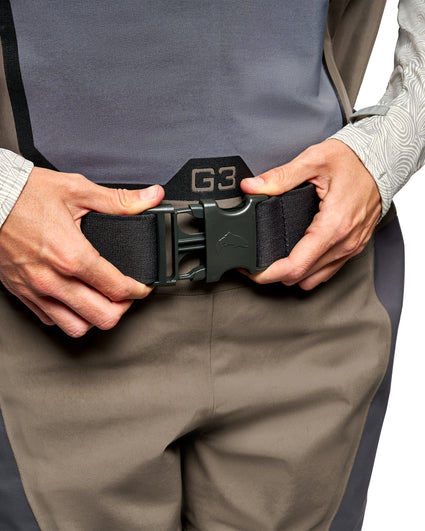 Women's Waders G3 Pro Guide Stockingfoot Close-up of a person wearing a black G-3 waist belt with a dark green quick-release buckle, shown being adjusted at the waist.