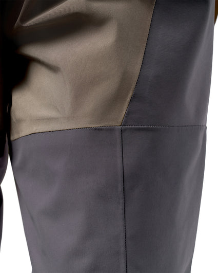 Women's Waders G3 Pro Guide Stockingfoot Close-up detail of a color-blocked waterproof jacket or waders, showing a dark gray lower section and a taupe-beige upper section with clean diagonal panel seams.
