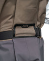 Men's G3 Pro Bootfoot Waders Close-up of a waist belt with a black G3 logo patch, worn over a taupe-brown outer layer and gray pants.