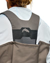 Men's G3 Pro Bootfoot Waders Close-up back view of a person wearing a gray and black back support harness vest over a white and light blue athletic jacket, with a taupe waterproof shell attached.