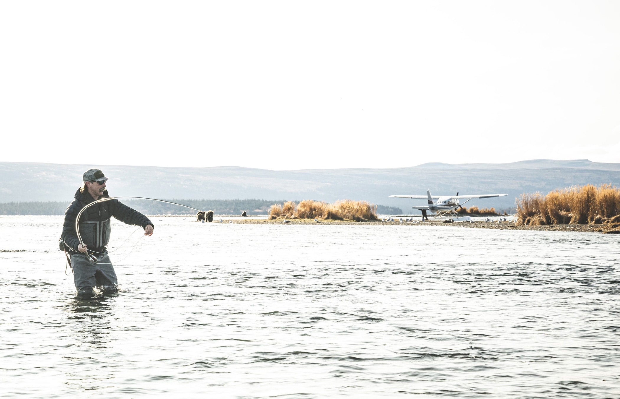 Person fly fishing in a body of water with a scenic background