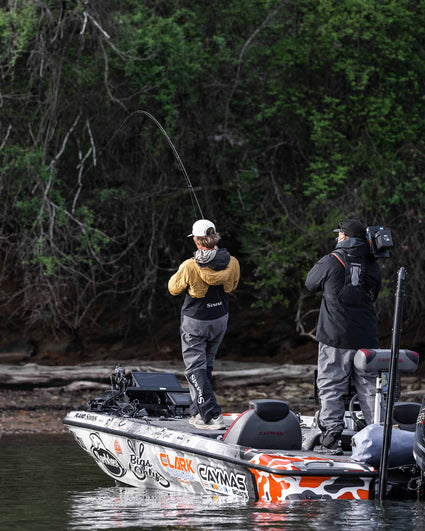 Two people on a boat fishing in a forested area